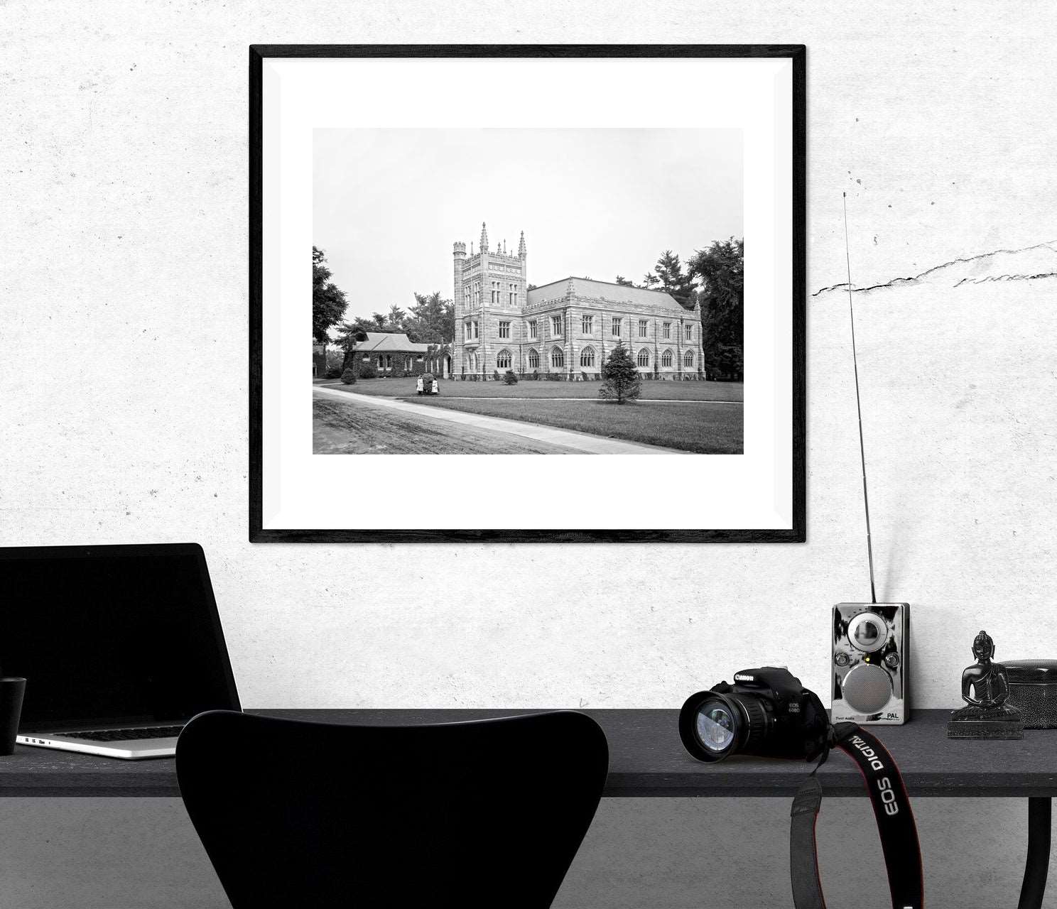 A framed print of Princeton University hanging on a white wal above a black desk