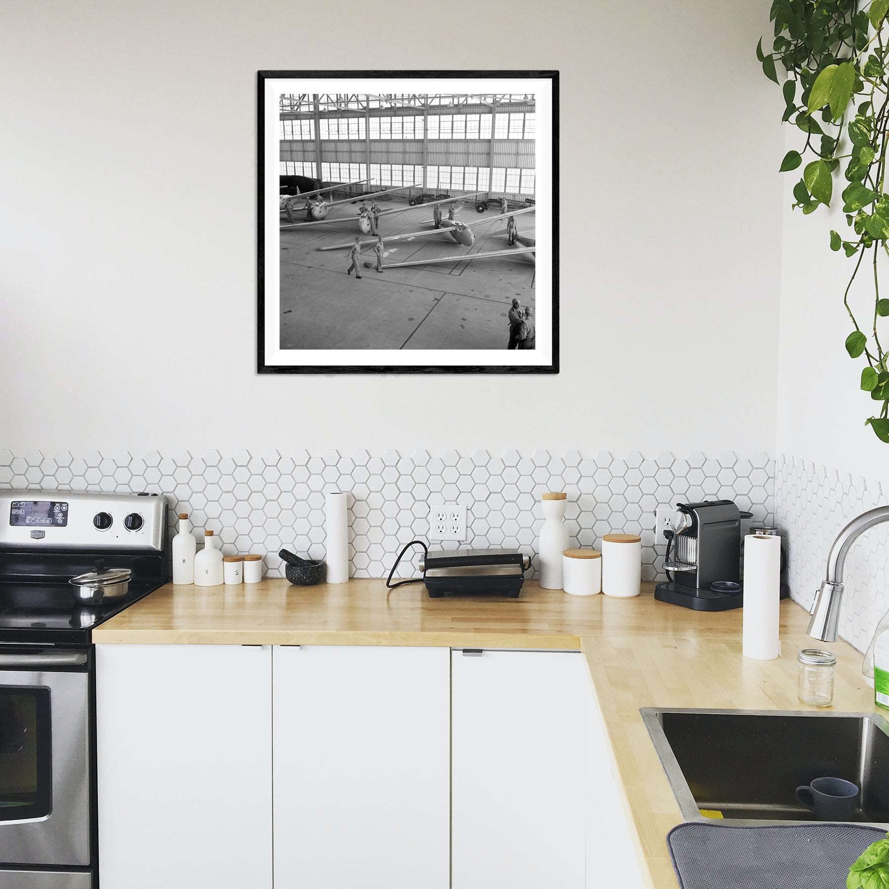 A photograph of a kitchen with a framed paper print of a vintage image of USMC planes