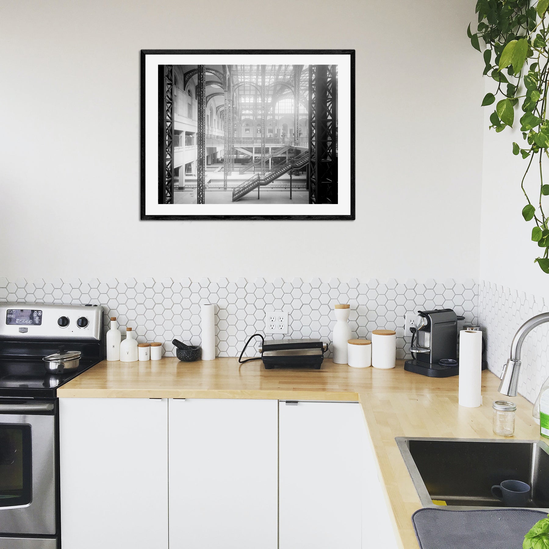 A framed print of a black and white photograph of Penn Station hanging in a modern kitchen