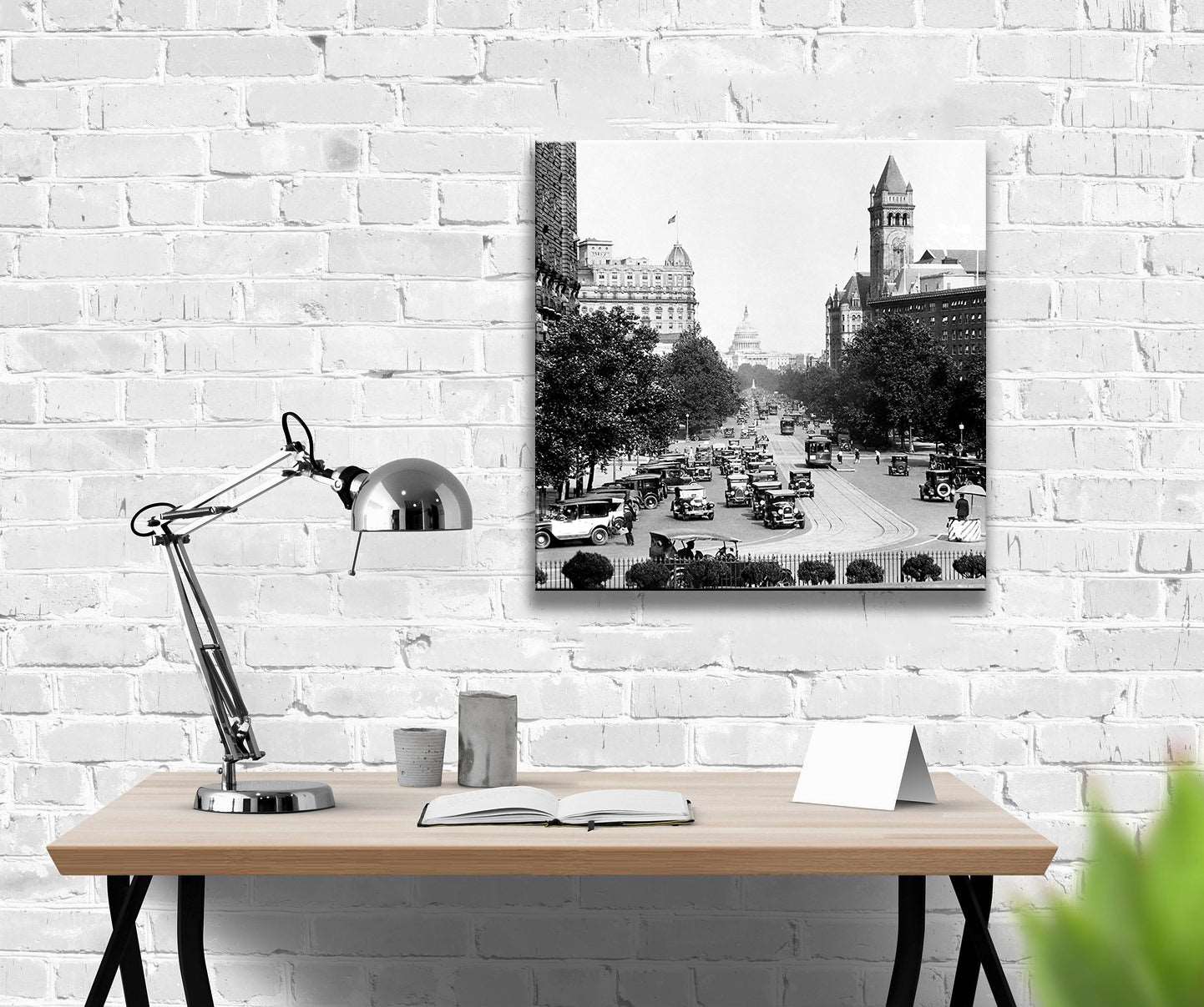 A canvas print of a photograph of Washington DC hangs on a brick wall above a wooden desk