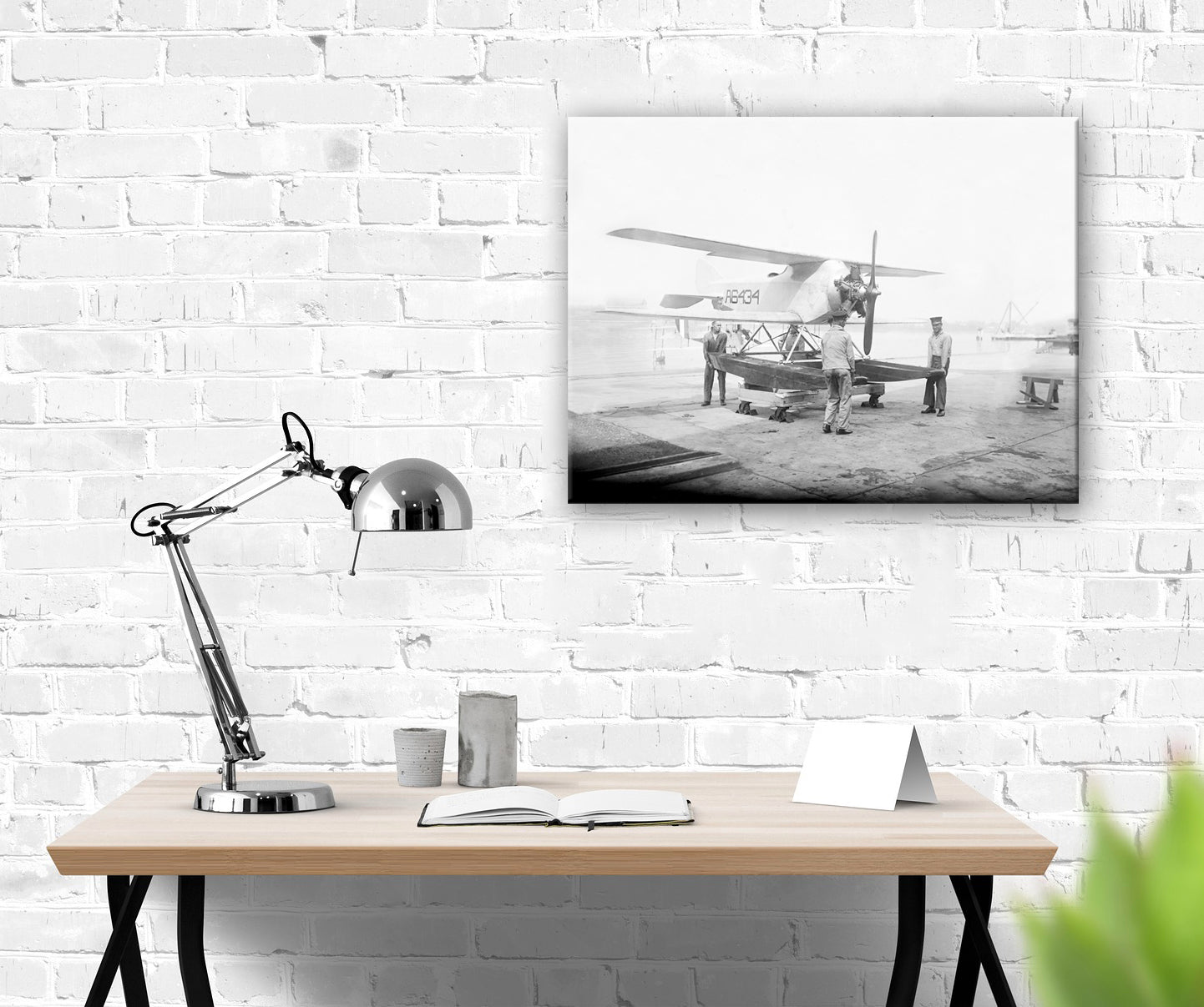 A canvas print of a submarine plane photograph hanging on a white brick wall