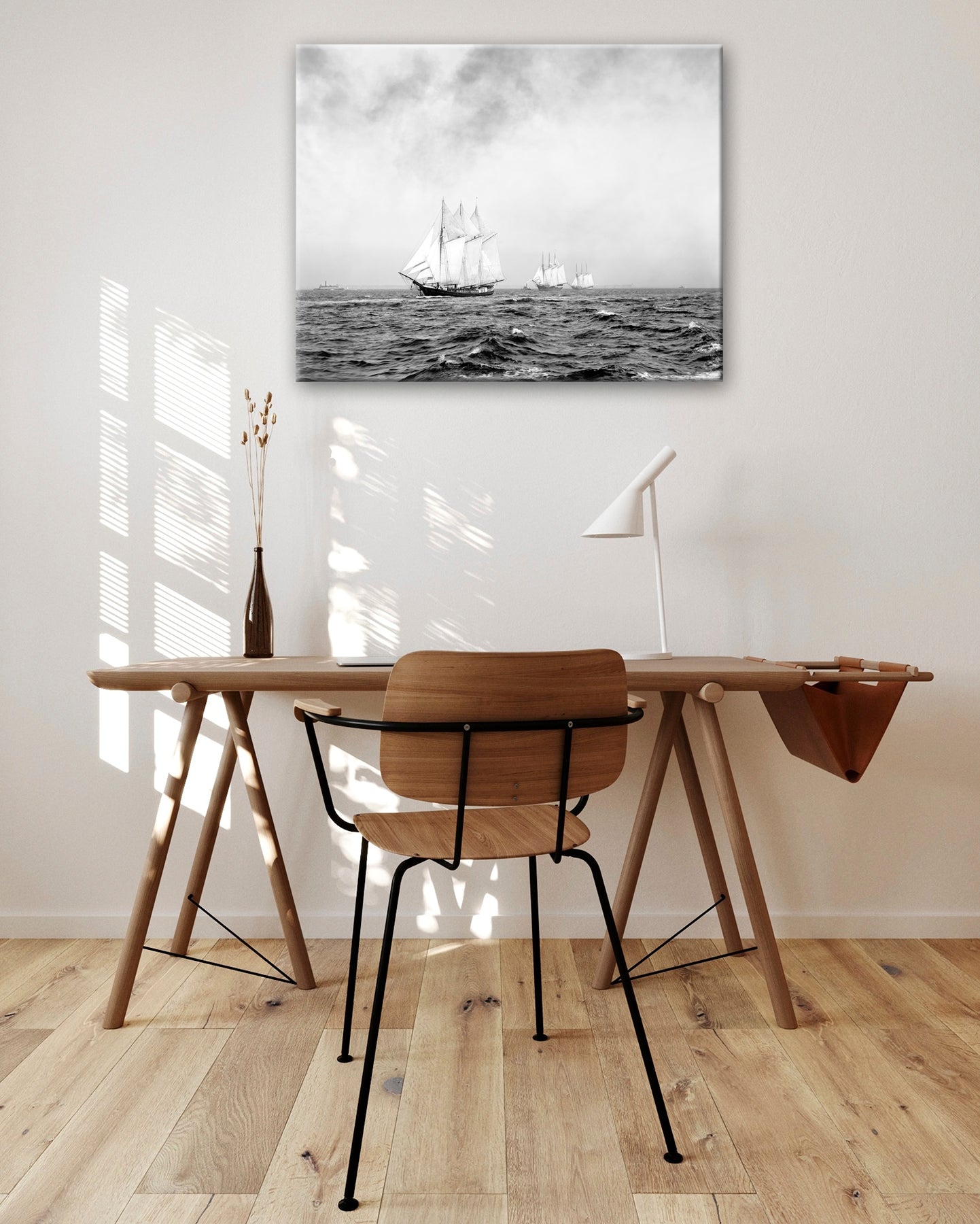 A canvas print of a vintage photogrpah of ships hanging on a wall above a brown desk