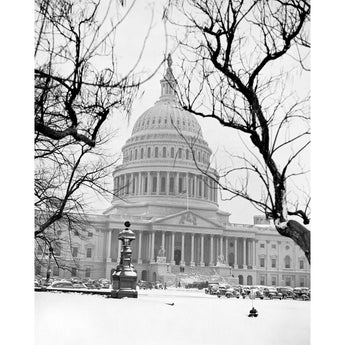 A black and white, vintage photograph of the US Capitol in snow