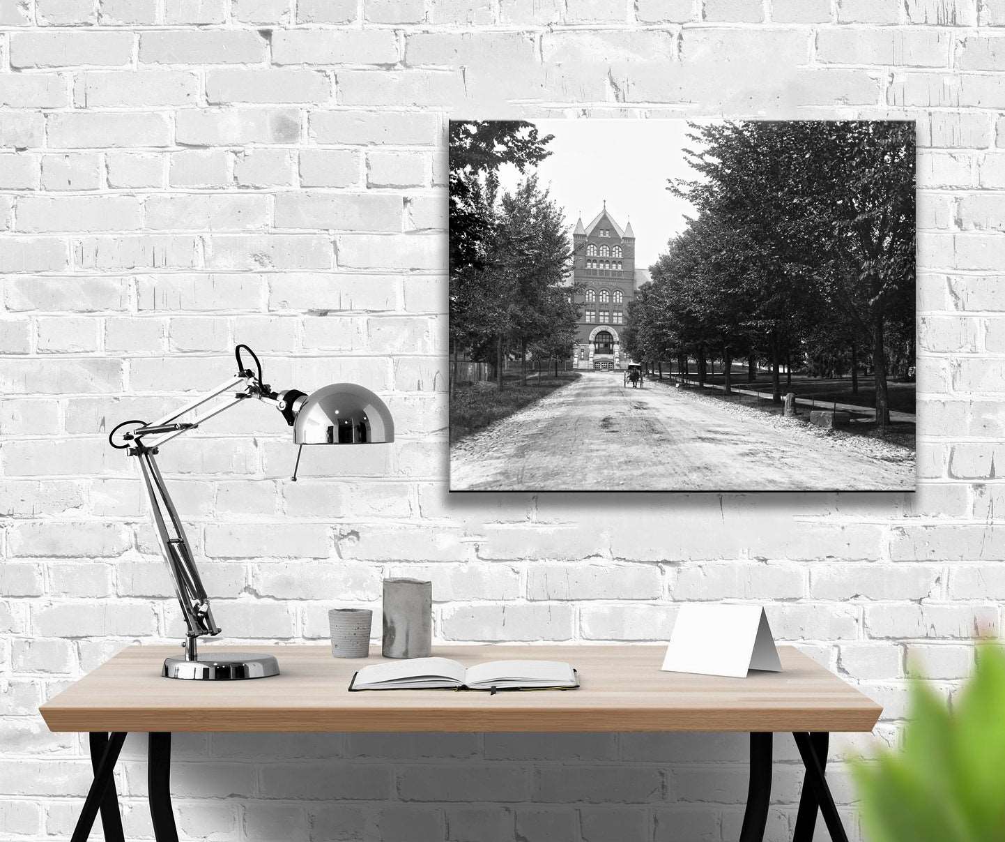 A canvas reproduction print of a vintage image of the University of Wisconsin hanging on a white brick wall