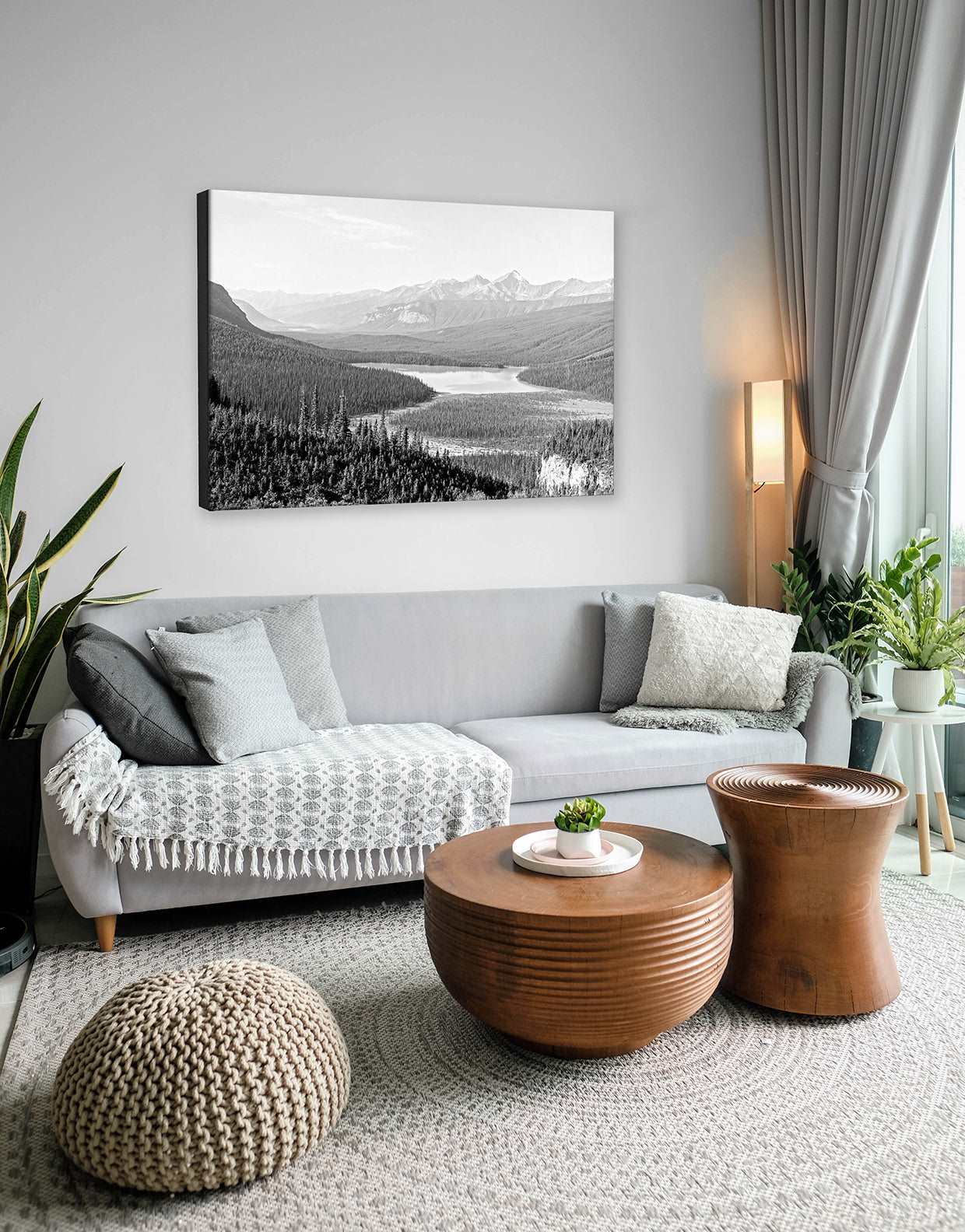 A neutral themed living room with a canvas print of a vintage landscape photograph hanging above the couch
