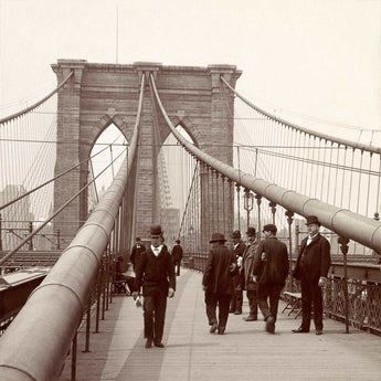 A sepia toned vintage photograph of people walking on the Brooklyn Bridge