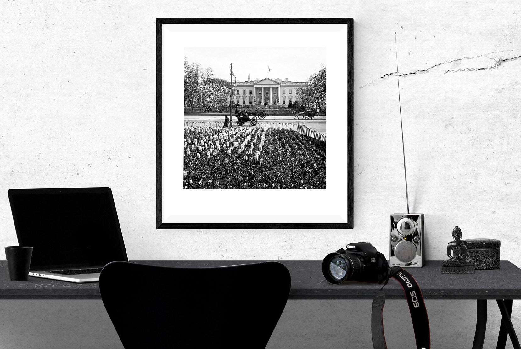 A digital mockup of a framed vintage photograph of the White House hanging above a work desk