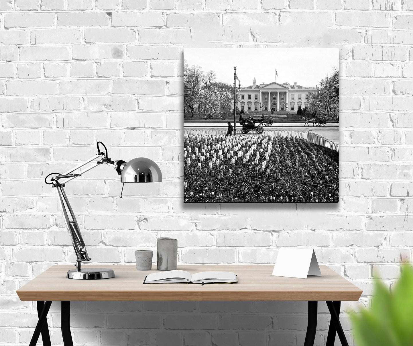 A rendering of a stretched canvas print of a vintage photograph of the White House, hanging on a white brick wall