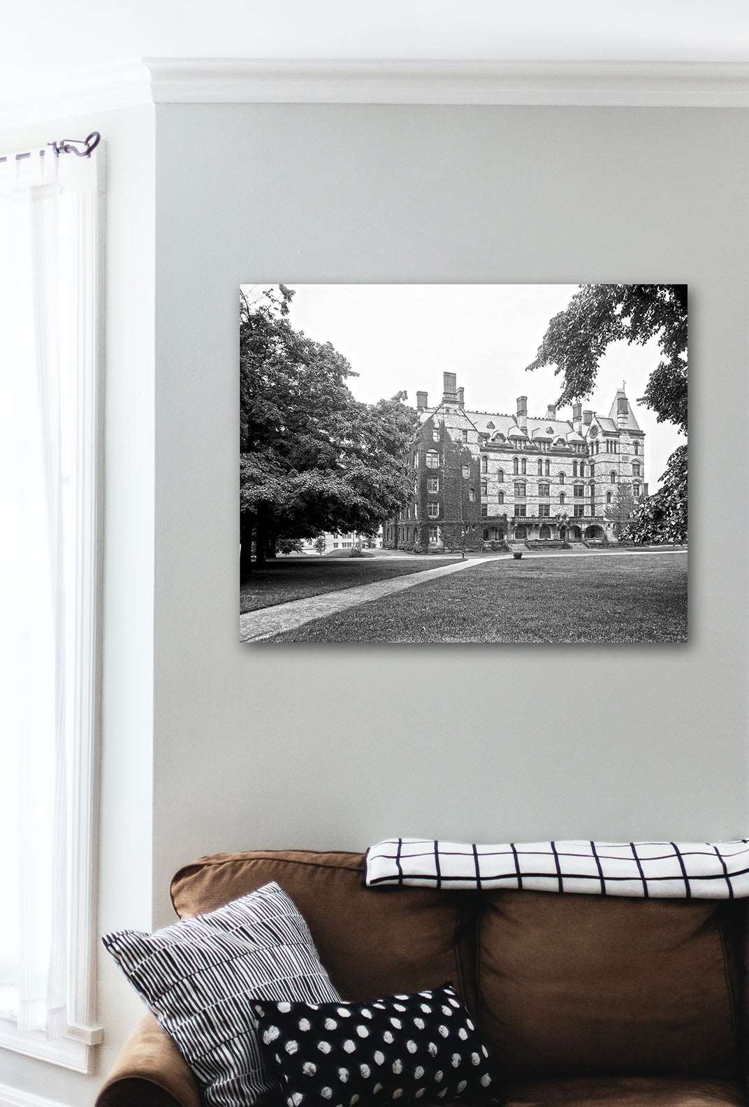 A canvas print of a photograph of Princeton University's Witherspoon Hall hanging above a brown couch