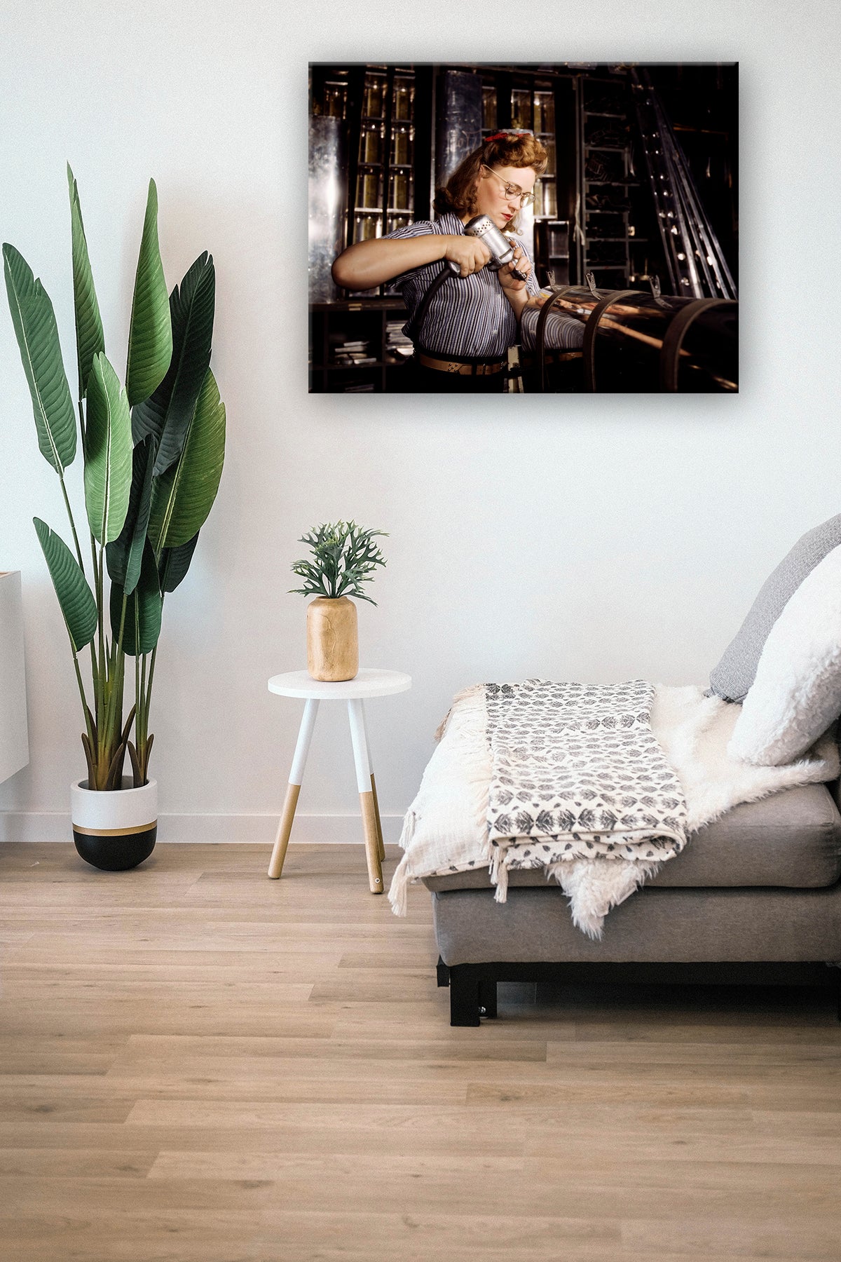 A digital mockup of a canvas print hanging on a wall, featuring a vintage photograph of a woman operating a hand drill