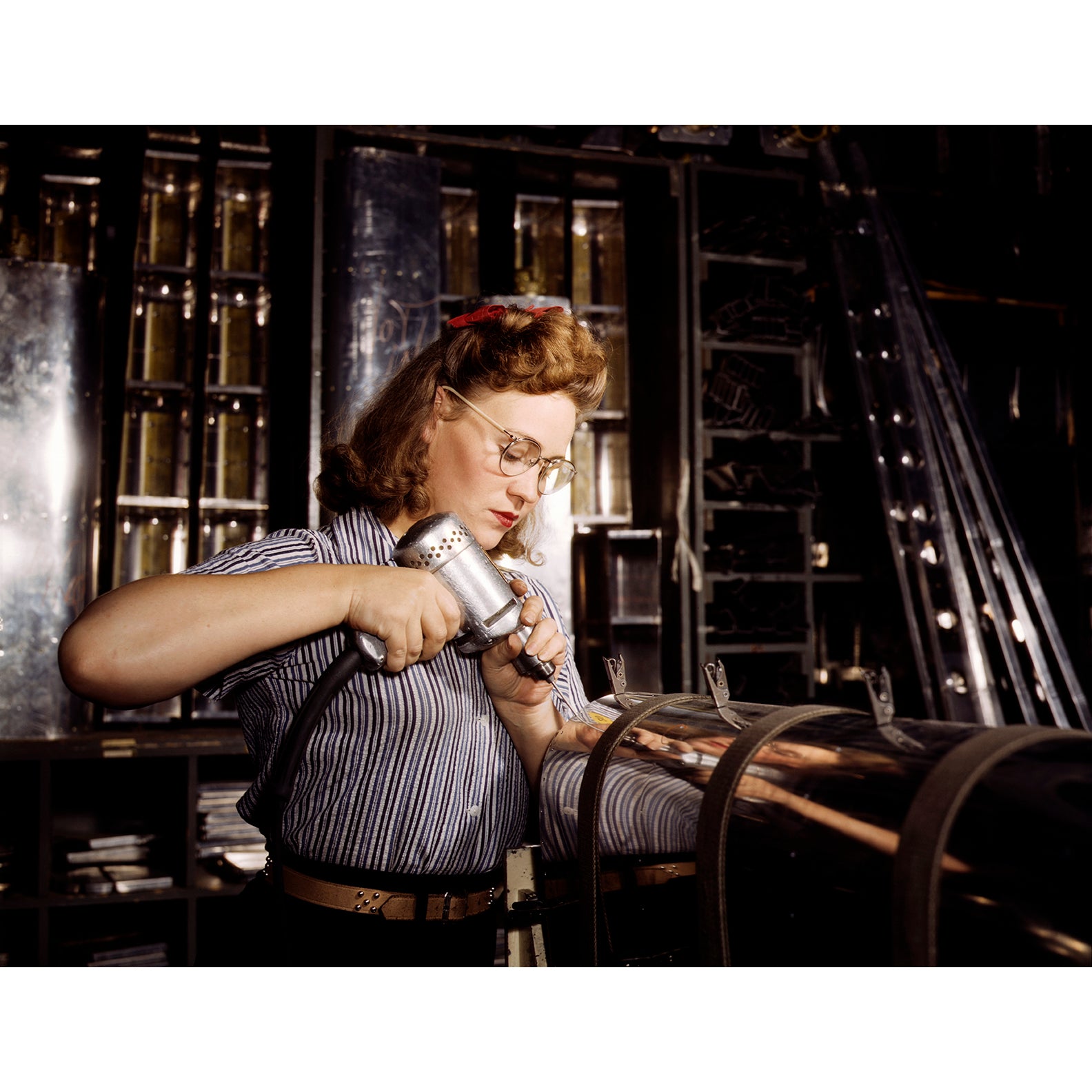 A vintage photogrpah of a young woman operating a hand drill at North American Aviation